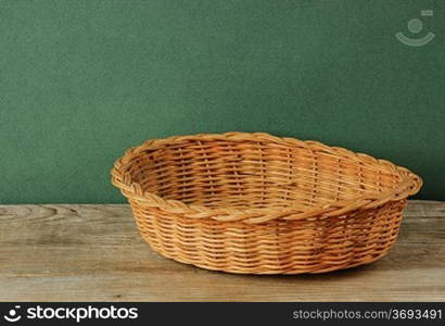 empty wicker basket on an old wooden table against grunge wall