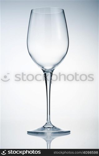 Empty wine glass on reflective surface over light background