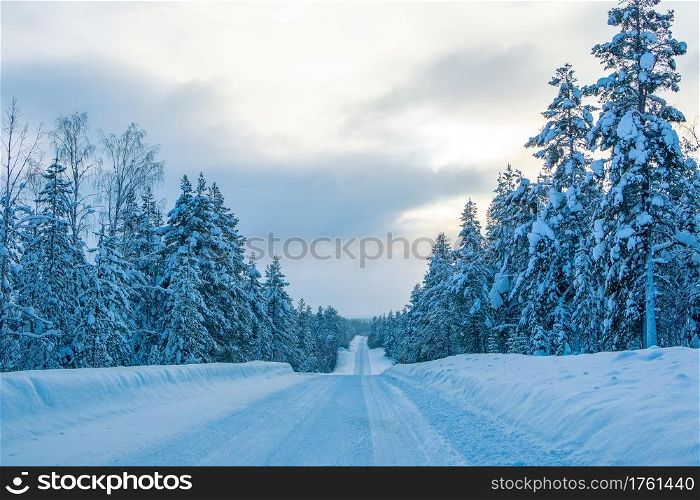 Empty winter highway through a snowy forest. Evening Finland. Empty Road in Winter Finnish Forest