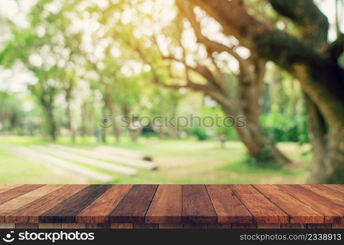 Empty wood table and defocused bokeh and blur background of garden trees in sunlight, display montage for product.