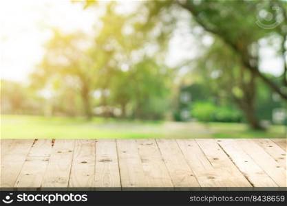 Empty wood table and defocused bokeh and blur background of garden trees in sunlight, display montage for product.