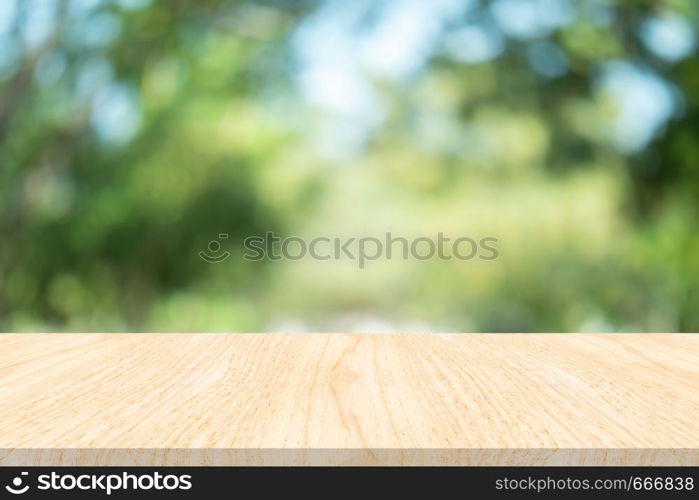 Empty wood table on blurred background copy space for montage your product or design , Blank brown board with abstract blurred green background.