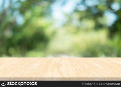 Empty wood table on blurred background copy space for montage your product or design , Blank brown board with abstract blurred green background.