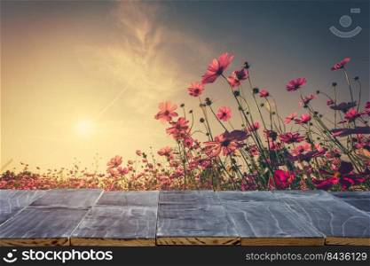 Empty wood table top for product display montage and cosmos flower and sunlight in garden.