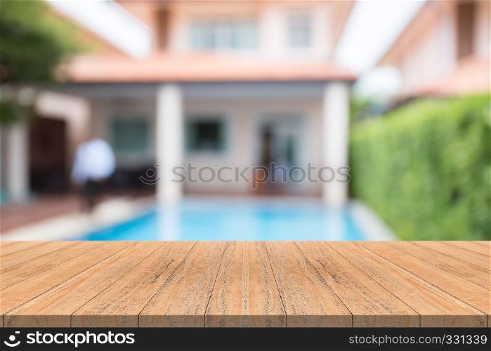 Empty wood table top on blurred background at swimming pool in garden
