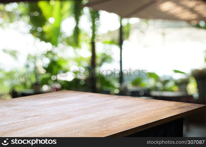 empty wood table top over blur in restaurant cafe background.