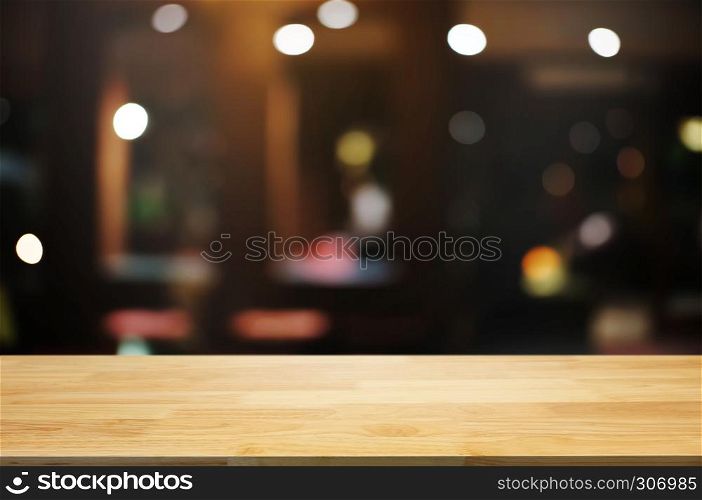 empty wood table top over blur night light in restaurant cafe background.