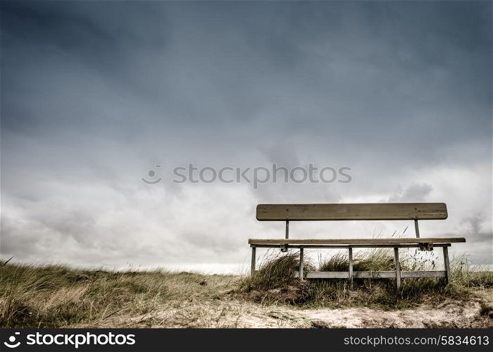 Empty wooden bench in cloudy weather