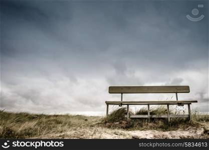 Empty wooden bench in cloudy weather