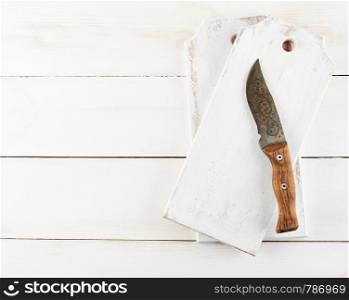 empty wooden cutting board and old knife on the white background, top view