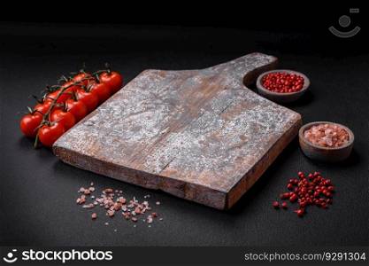 Empty wooden cutting board with cracks and scuffs located on a dark concrete background
