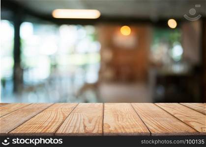 empty wooden desk over blurred coffee shop background
