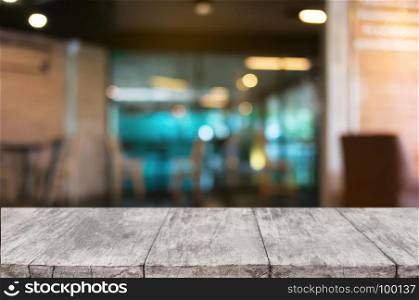 empty wooden desk over blurred coffee shop background