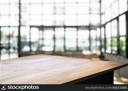empty wooden desk over blurred coffee shop cafe background