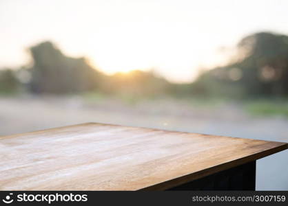 empty wooden desk over blurred montage home garden with sunset background