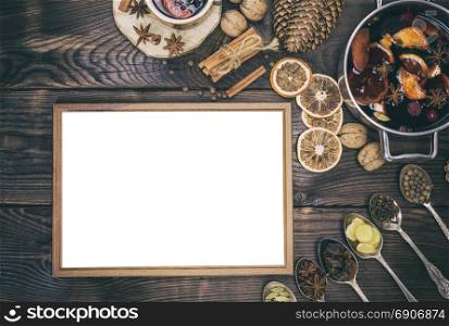 empty wooden frame and wine mulled wine with ingredients on a brown wooden background