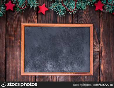 empty wooden frame on a brown background of boards, a fan of green spruce branches with a festive decor