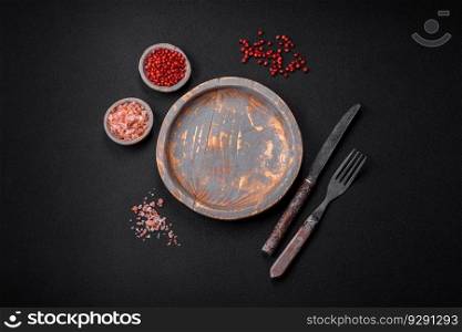Empty wooden plate, knife, fork and cutting board set on textured concrete background