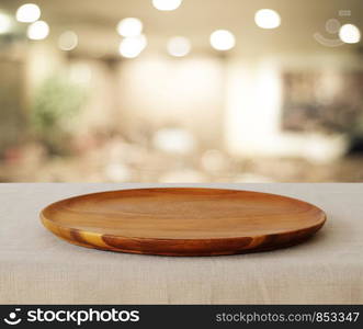 Empty wooden round tray over blurred cafe with bokeh light background, food and product display montage