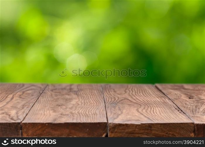 Empty wooden table against green natural background