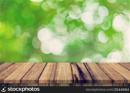 Empty wooden table and abstract blurred green bokeh leaves background texture, display montage with copy space.