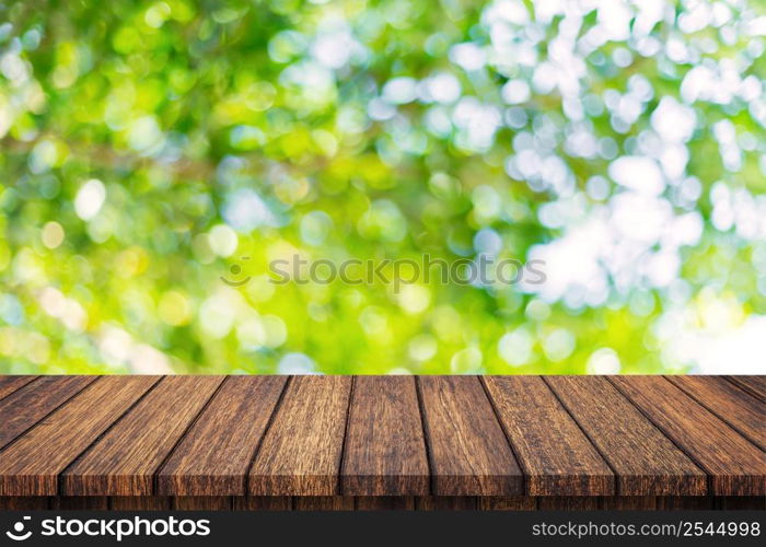 Empty wooden table and abstract blurred green bokeh leaves background texture, display montage with copy space.