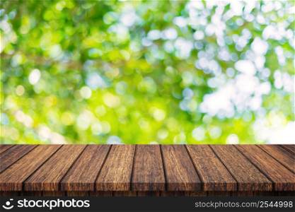 Empty wooden table and abstract blurred green bokeh leaves background texture, display montage with copy space.