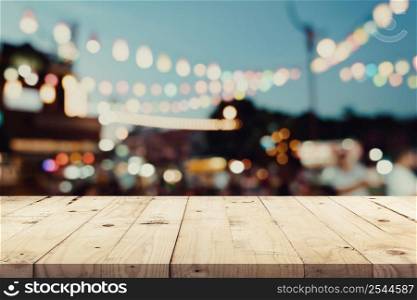 Empty wooden table and blurred background at night market festival people walking on road with copy space, display montage for product.