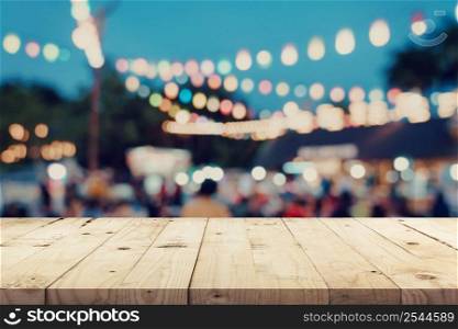 Empty wooden table and blurred background at night market festival people walking on road with copy space, display montage for product.