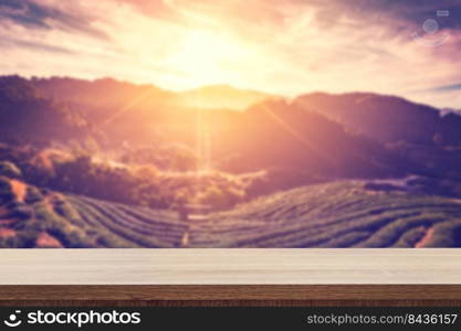 Empty wooden table for product placement or montage and blurred tea field and sunrise vintage.