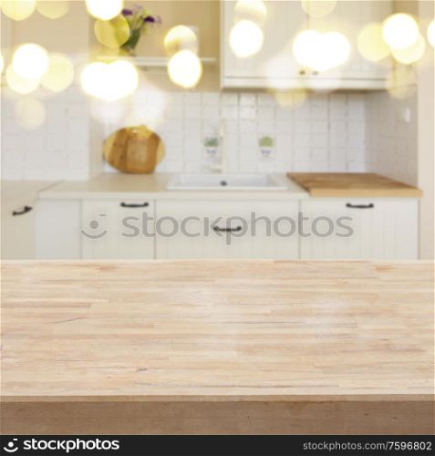 empty wooden table in a withe modern kitchen with bokeh lights in background. table in a kitchen