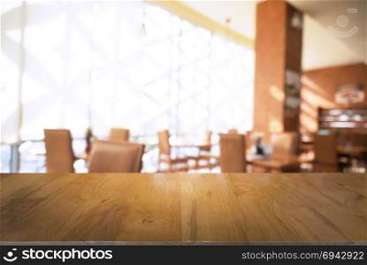 Empty wooden table in front of abstract blurred background of coffee shop . can be used for display Mock up of product.