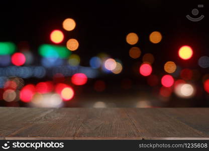 Empty wooden table in front of abstract blurred bokeh light of Cafe, restaurant at night.