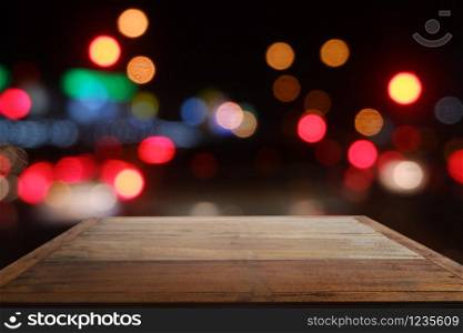 Empty wooden table in front of abstract blurred bokeh light of Cafe, restaurant at night
