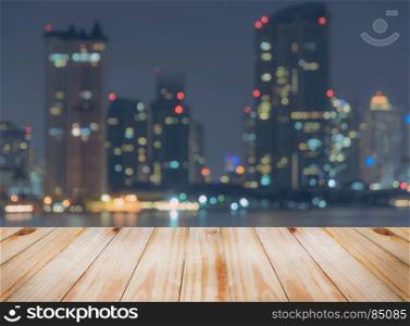 Empty wooden table top with blurred city skyline background at night, can be used for montage or display your products