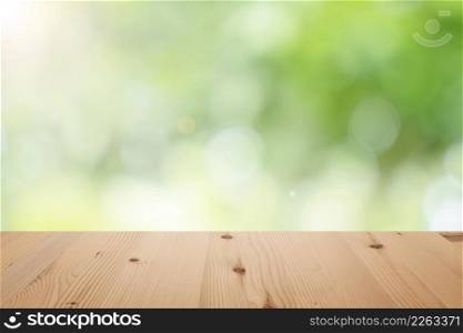 Empty wooden table top with blurred defocus natural green bokeh background, aesthetic creative design