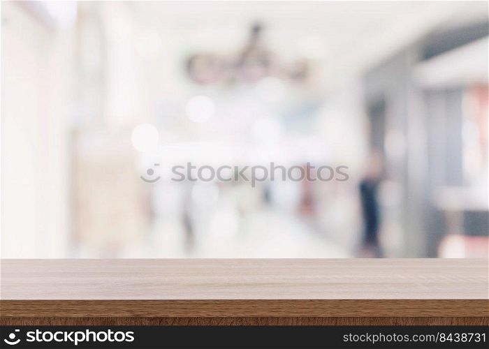 Empty wooden table top with blurred modern shopping mall background for product display and montage.