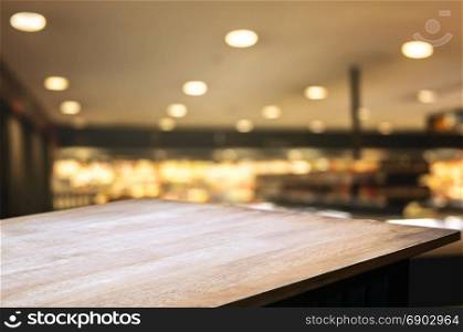 empty wooden table top with blurred with bokeh light of shopping mall background, used for display or montage your product