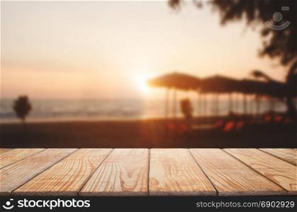 empty wooden table with blurred beach and sunset background