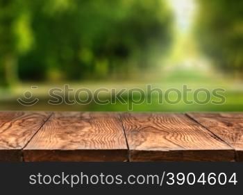 Empty wooden table with blurred city park on background, natural background with bokeh