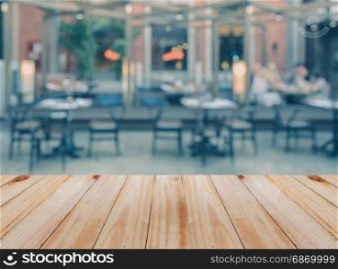 Empty wooden table with blurred outdoor restaurant background. For product display business concept.