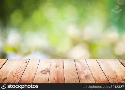 Empty wooden table with foliage bokeh background.