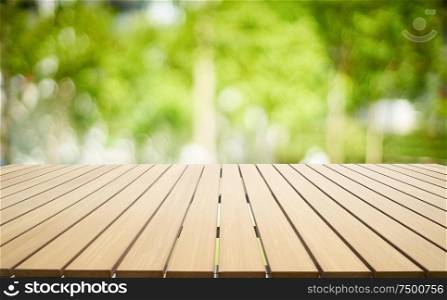 Empty wooden table with out of focus green park background .