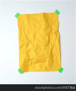 empty yellow crumpled sheet of paper glued with green sticky pieces of paper on a white background, place for text