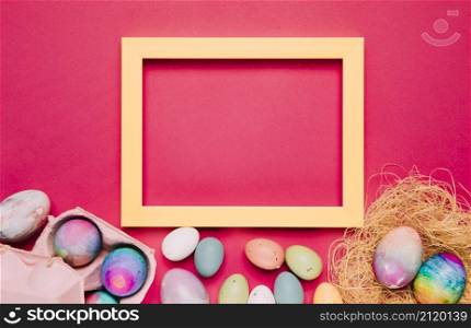 empty yellow frame with colorful easter eggs pink background