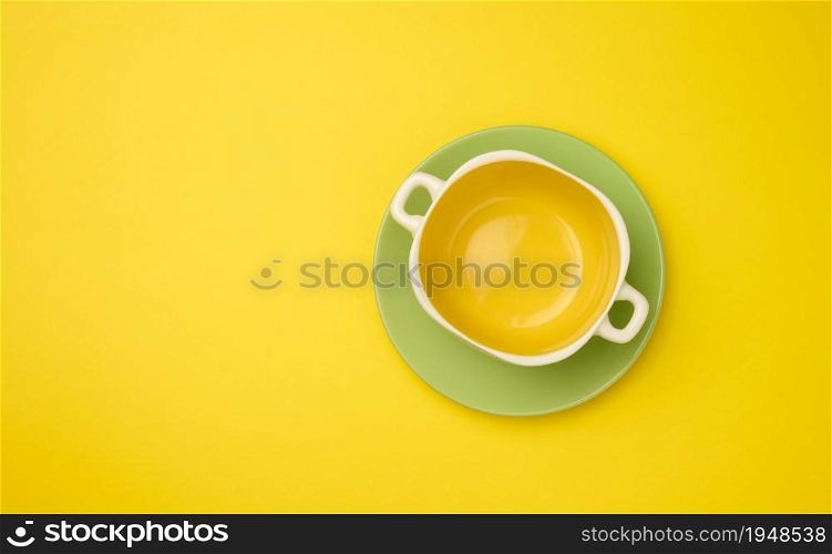 empty yellow soup plate on a yellow bacground, top view