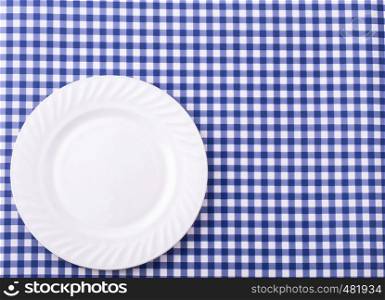 Empy plate on the tablecloth in a cage. View from above with copy space