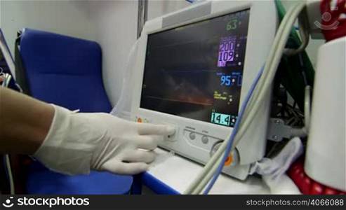 EMT paramedic provide emergency medical care to person in ambulance monitoring high blood pressure on screen of multiparameter patient monitor pan shot closeup