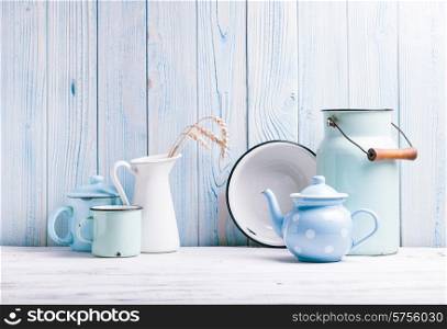 Enamelware on the kitchen table over blue wooden wall. Enamelware still life