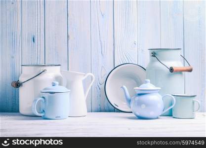 Enamelware on the kitchen table over blue wooden wall. Enamelware still life